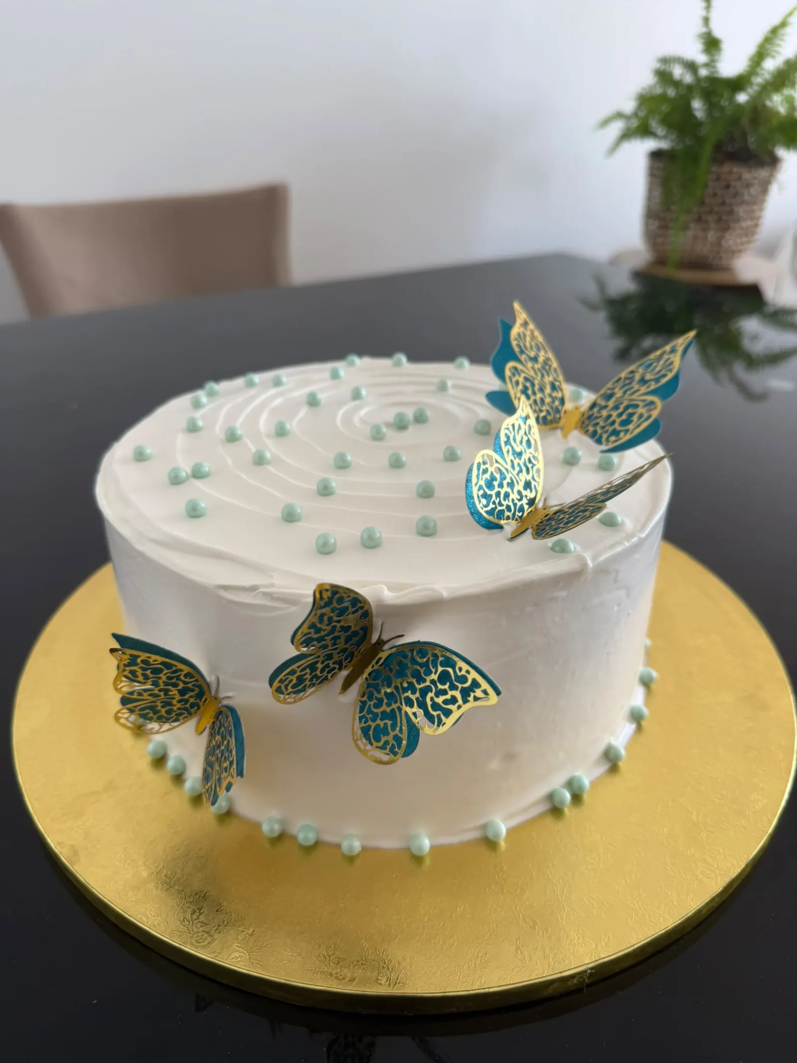 Bolo branco com borboletas douradas e azuis e pérolas verde-água